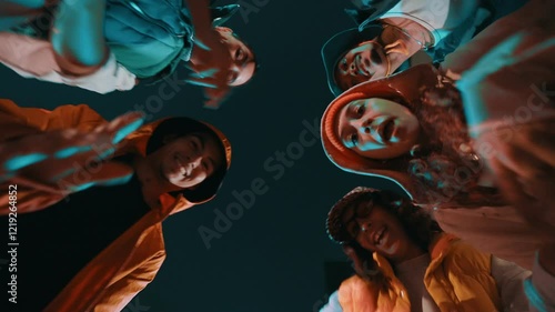 Group of young trendy friends looking down on a circle, moving, dancing and having fun at night