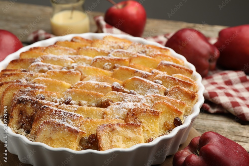 Delicious bread pudding with raisins, powdered sugar and apples on wooden table, closeup Delicious bread pudding with raisins, powdered sugar and apples on wooden table, closeup