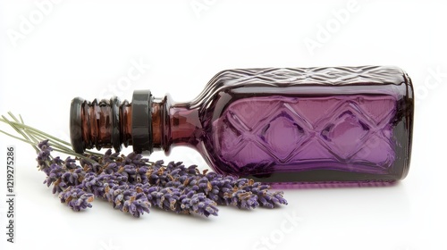 A bottle of organic lavender essential oil, placed beside a few dried lavender flowers, on a white isolated background photo