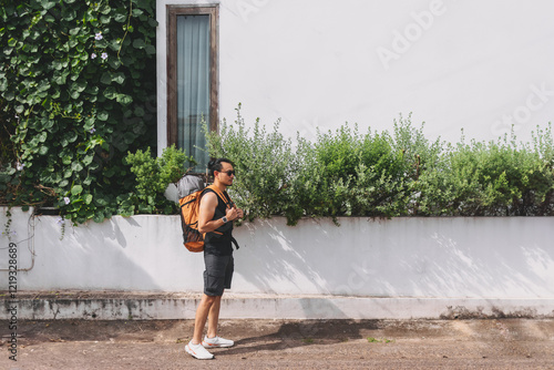 Tourist backpacker walking on the street passing white hotel building. photo