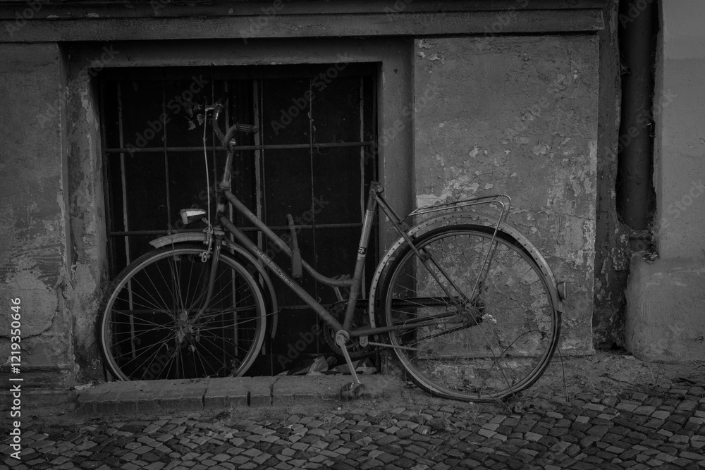 an old rusty bicycle leaning against an old house wall