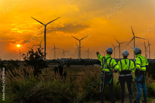 Silhouette back view female and males wind turbine engineers working in wind power plant until sunset photo