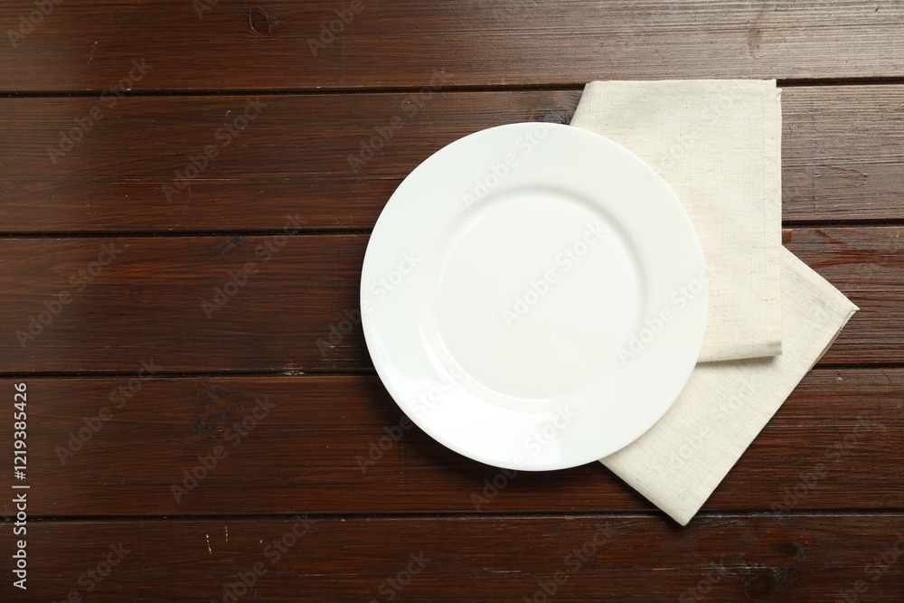 Light napkin and empty plate on wooden table, top view. Space for text Light napkin and empty plate on wooden table, top view. Space for text