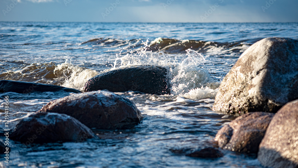 Naklejka premium landscape with the seashore, windy winter day, water splashes, icy stones on the seashore, Baltic Sea, Latvia