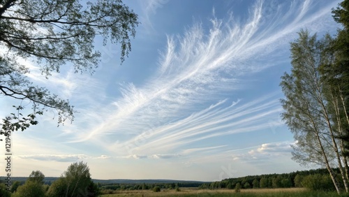 Delicate wisps of cloud drift across a pale blue sky, light and airy feel, subtle color gradations photo