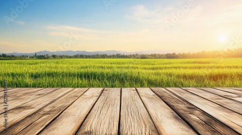 Scenic view of a wooden deck overlooking a lush green field under a bright sunset sky photo