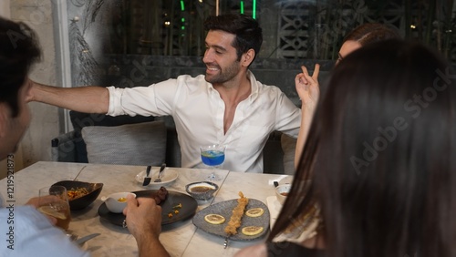 Woman taking sefie using smartphone with friends posing with special cocktail drinks surrounded by grill and fried meat special menu featuring unique chef table menu on table at restaurant. Vinosity. photo