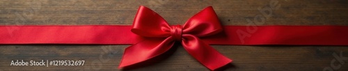 Knotted red silk ribbon tied in a bow on a wooden surface with a minimalist background, knotted ribbon, textured surface