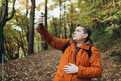 Sad angry blonde man got lost and could not find an internet connection on phone while hiking alone in the forest. Road trip, transport, travel, technology and people concept. High quality photo