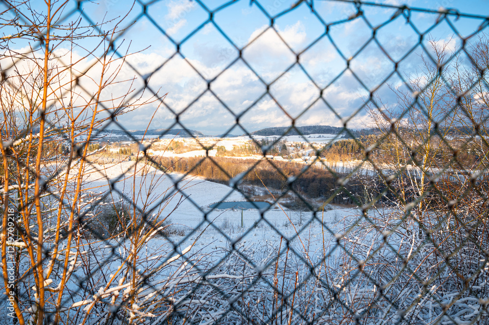 Wintry landscape of Bavaria (Bayern), Germany in winter as seen through a metal fence Wintry landscape of Bavaria (Bayern), Germany in winter as seen through a metal fence