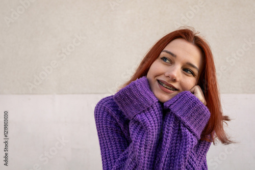 Smiling Redhead Girl with Braces Wearing a Purple Knitted Sweater	
