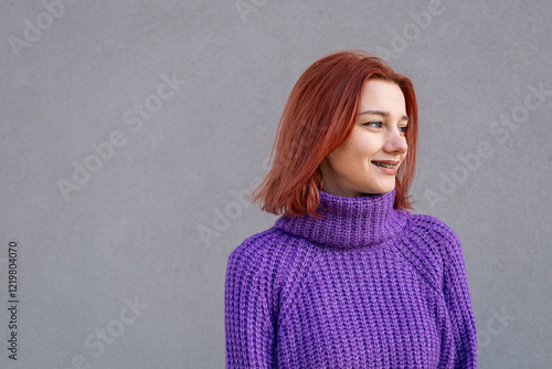 Smiling Redhead Girl with Braces Wearing a Purple Knitted Sweater	
