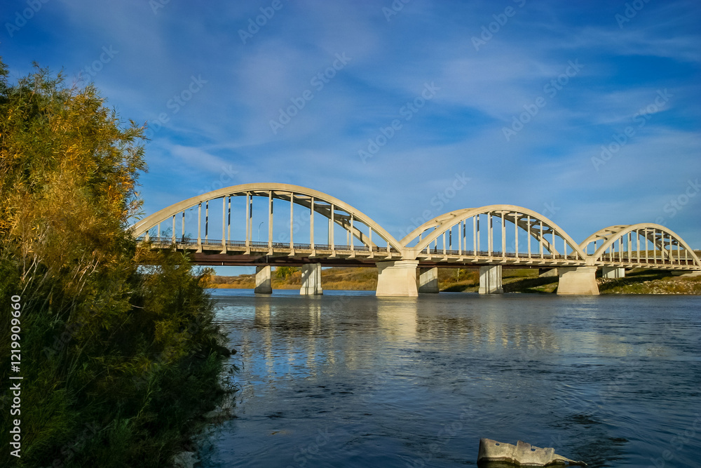Naklejka premium A bridge spans a river with a blue sky in the background