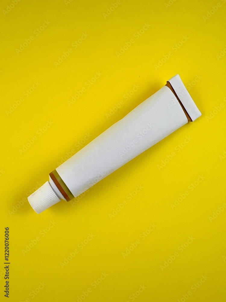 White tube commonly used for Pharmaceutical use of chemical product such as adhesives isolated on yellow background White tube commonly used for Pharmaceutical use of chemical product such as adhesives isolated on yellow background