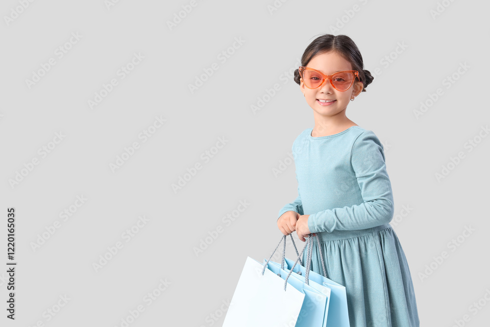 Cute little girl with shopping bags on light background Cute little girl with shopping bags on light background