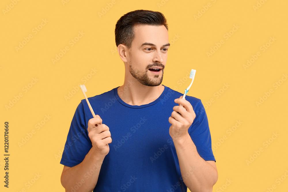 Handsome man with toothbrushes on yellow background Handsome man with toothbrushes on yellow background