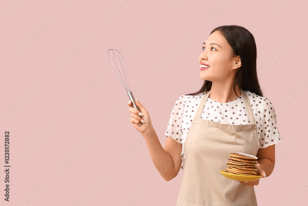 Young Asian woman with tasty pancakes and whisk showing something on pink background Young Asian woman with tasty pancakes and whisk showing something on pink background