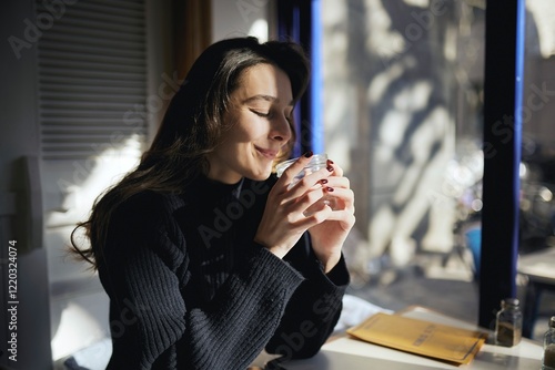 A woman is sitting at a table with a glass of water in front of her