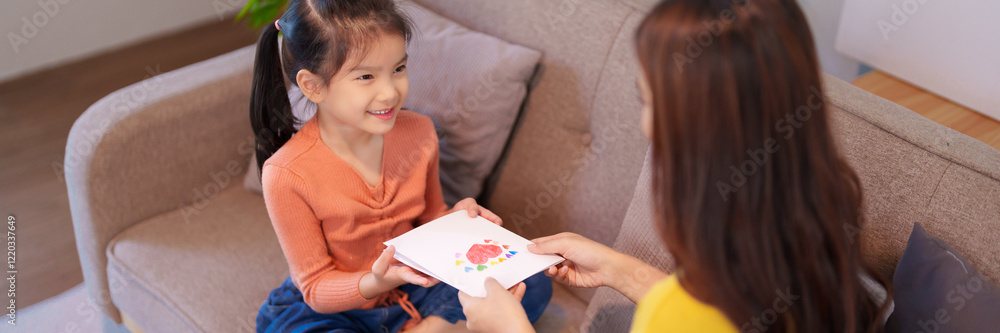 A young daughter surprises her mother with a handmade card, creating a heartfelt moment of love and appreciation. A young daughter surprises her mother with a handmade card, creating a heartfelt moment of love and appreciation.