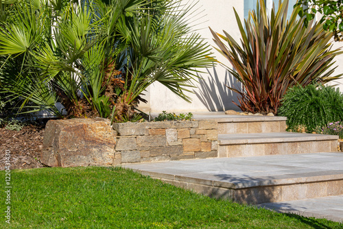 Charmant petit jardin paysagé et ses plantes fleuries au pied d'une maison au printemps.