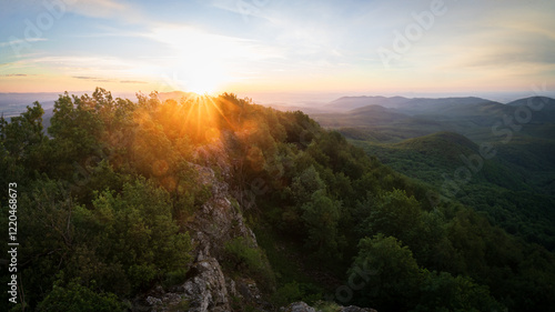 Photography Sun rising over beautiful hilly landscape with rocks, deciduous forest and trees