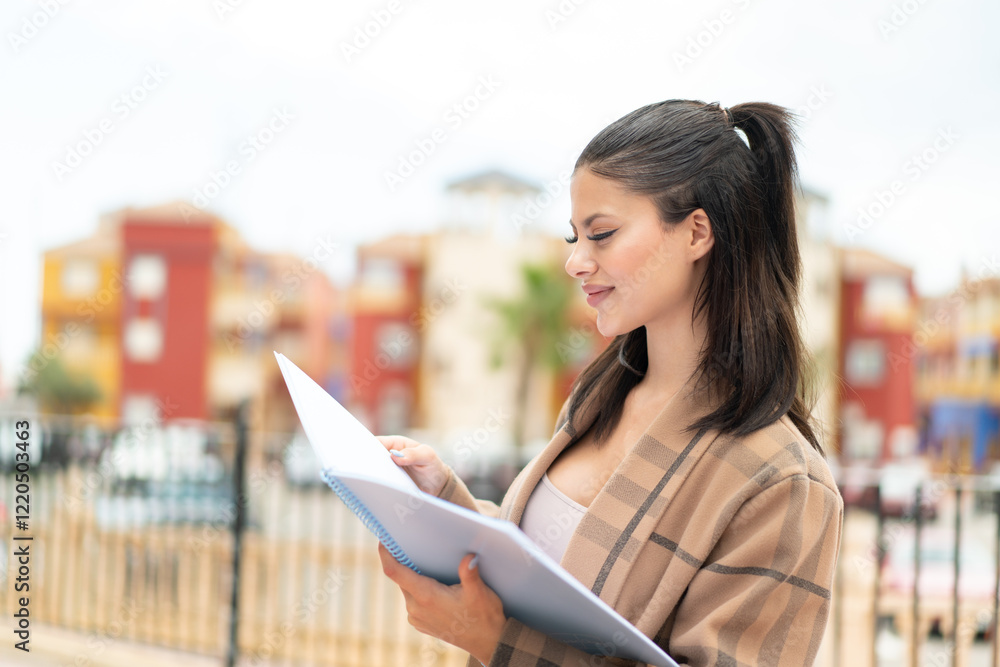 Obraz premium Young pretty woman at outdoors holding a notebook