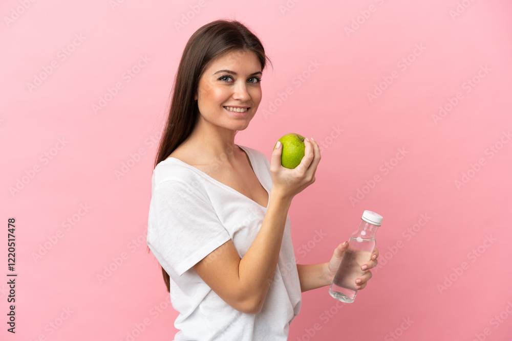 Young caucasian woman isolated on pink background with an apple and with a bottle of water Young caucasian woman isolated on pink background with an apple and with a bottle of water