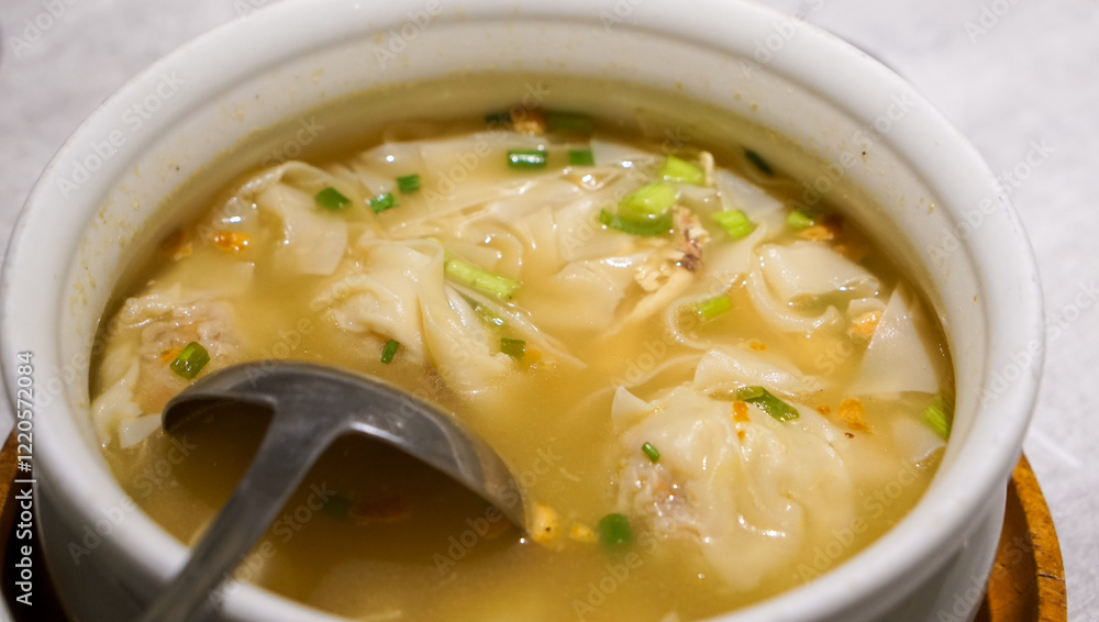 Obraz premium Pancit Molo, a classic Ilonggo soup with dumplings, shredded chicken, and a rich savory broth, served hot at a restaurant in Iloilo, Philippines—comfort food at its finest.