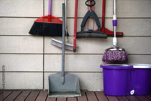 An assortment of essential cleaning tools hang neatly on a tiled wall, ready for any household task