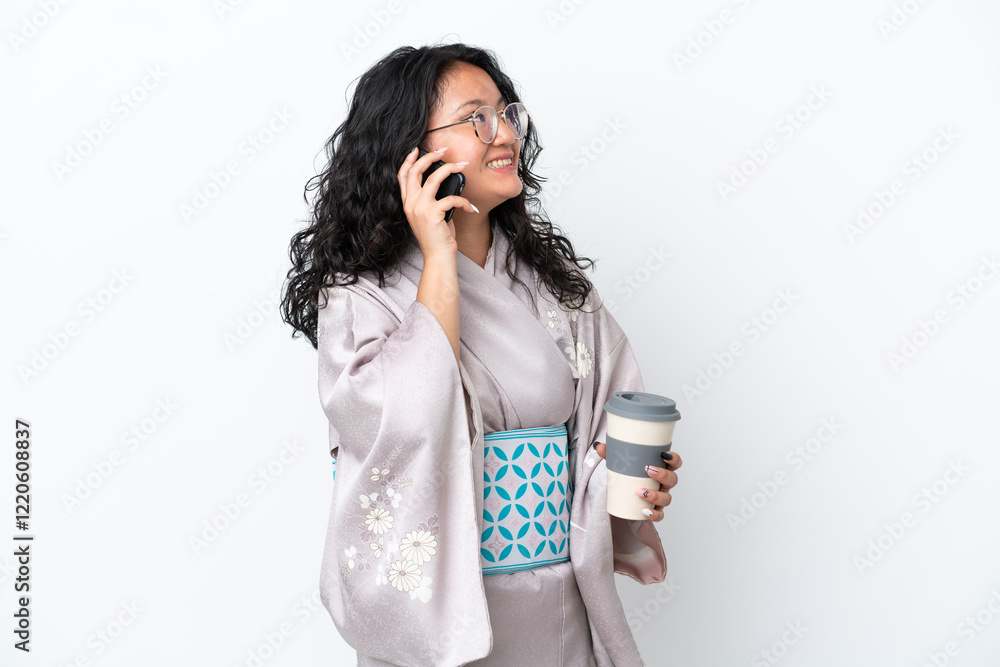 Young asian woman wearing kimono isolated on white background holding coffee to take away and a mobile Young asian woman wearing kimono isolated on white background holding coffee to take away and a mobile