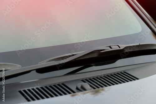 Windshield wipers are folded and stored on the windshield of the car. Clean car windshields and hoods without rain stains.