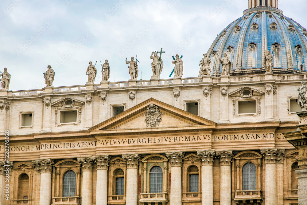 A large building St. Peter's Church of Vatican in Italy with a blue dome and a cross on top. The building has a lot of statues on it A large building St. Peter's Church of Vatican in Italy with a blue dome and a cross on top. The building has a lot of statues on it