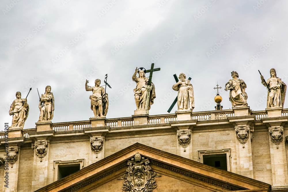 Obraz premium A large building St. Peter's Church of Vatican in Italy with a blue dome and a cross on top. The building has a lot of statues on it