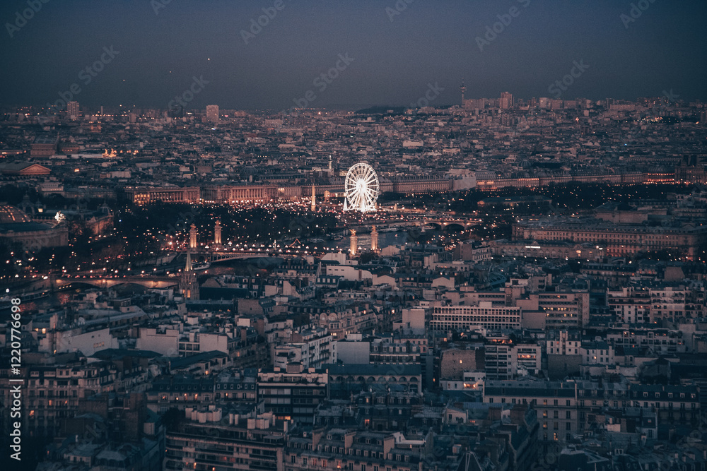 Obraz premium A city skyline of Paris with a tall building in the middle. The sky is dark and the city is lit up