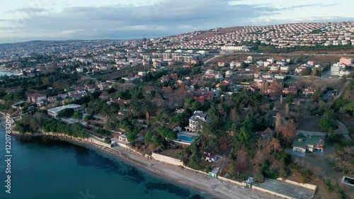 Drone flying over a coastal city with blue sea at sunset with clear sky in Guzelce, Istanbul, Turkey photo