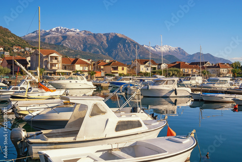 Beautiful winter Mediterranean landscape. Montenegro, Tivat city,  view of Marina Kalimanj on sunny day. Fishing boats in harbor.  Snowcapped Lovcen mountain photo