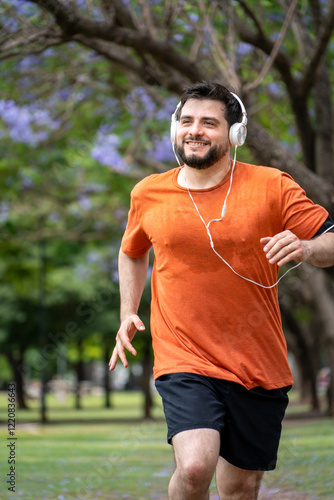 Hombre entrenando, trotando y sonriendo en un parque urbano en un hermoso día soleado. Hombre feliz corriendo photo