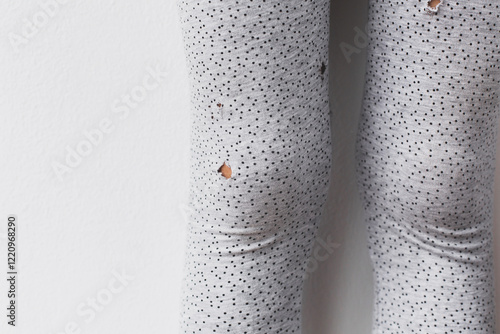 Close-up of torn gray leggings with black dots, illustrating wear and tear, damage, or everyday clothing imperfections, isolated against a white background photo