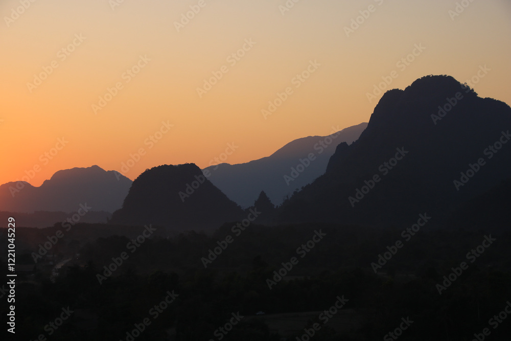 Golden evening sky over mountains at sunset, Vang Vieng, Laos.