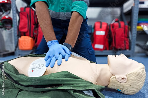 Close-up of middle-aged Asian male hands performing cardiopulmonary resuscitation (CPR) on a training dummy. Vital techniques include defibrillation, chest compressions, and maintaining the airway.