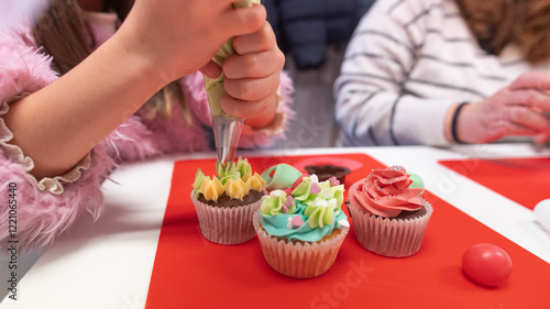 Fotografi Young girl decorating cupcakes during a baking class preparing muffins and cupca