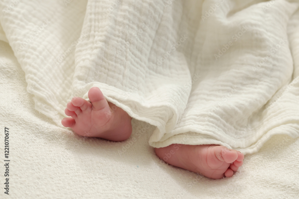 Close-up of newborn baby feet partially covered by a soft white blanket. Scene portrays innocence, warmth, tenderness, and the fragility of early childhood moments. Close-up of newborn baby feet partially covered by a soft white blanket. Scene portrays innocence, warmth, tenderness, and the fragility of early childhood moments.
