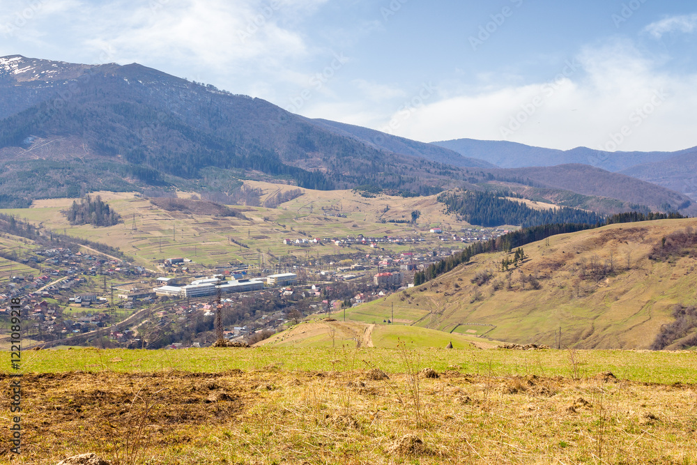 Naklejka premium carpathian countryside scenery with fields on the hills and village in the valley. natural environment. mountainous rural landscape of ukraine on a sunny day in spring. borzhava ridge