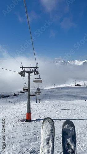 ski lift at the resort, winter sports, alpine skiing and snowboarding, snow-capped mountain peaks on a sunny winter day vertical video
