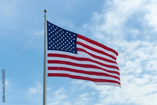 A large American flag waving against a backdrop of soft, scattered clouds and a bright blue sky photo