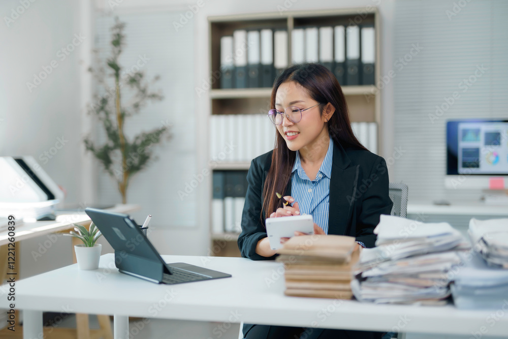 Asian businesswoman taking notes while having video call on tablet in office Asian businesswoman taking notes while having video call on tablet in office