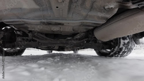 The operation of the car suspension in motion. Camera at the bottom of the car. The car is driving in the snow