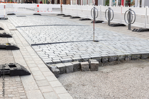 Construcion site of pavement granite cobblestone road in old city center installation or renovation repair. Roadworks stonework at pedestrian area. Paved sidewalk reconstruction. Urban development photo