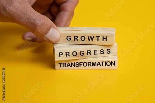 An image featuring three wooden Jenga blocks arranged neatly on a solid yellow background. Each block is engraved with an inspirational word or phrase