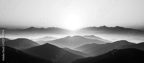 Dramatic moody and atmospheric monochromatic mountainscape with misty hazy fog and dramatic lighting at sunrise or sunset  Rugged craggy peaks silhouetted against the horizon under a dramatic